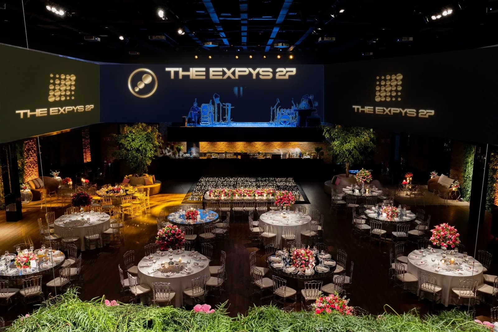 A room wrapped in screens over rounds of ten, THE EXPYS 27 above the stage
