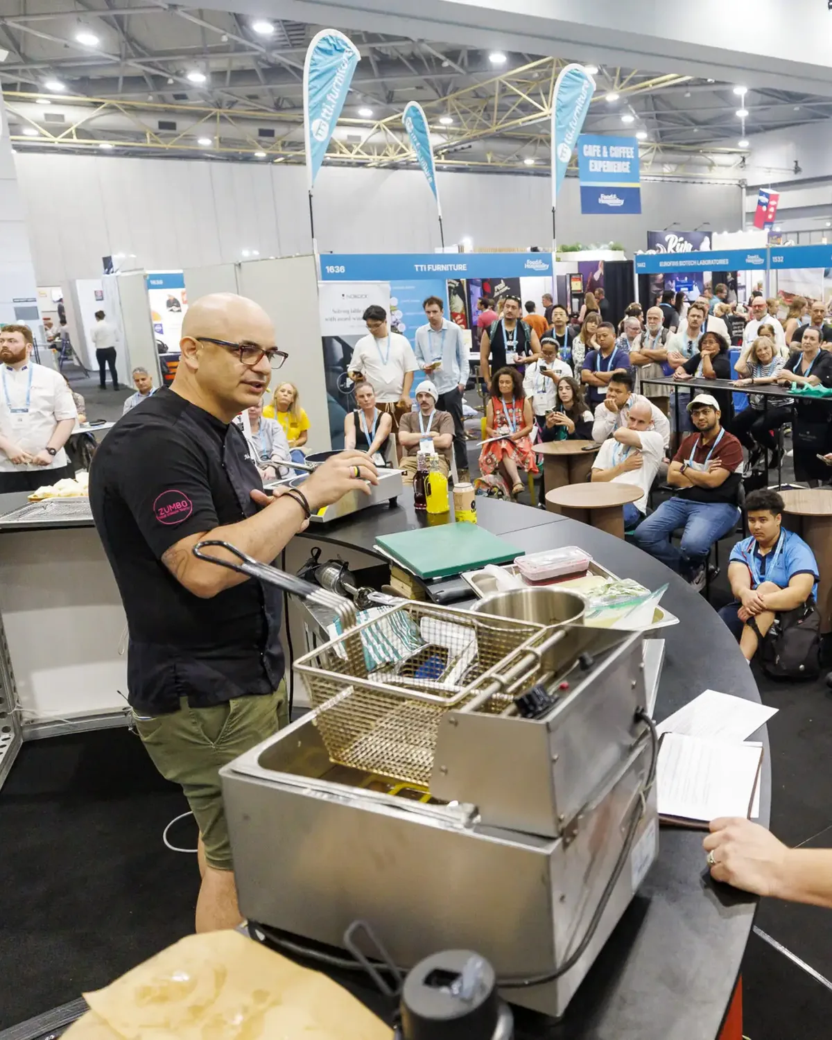 A chef cooking for a crowd at a food service expo stage