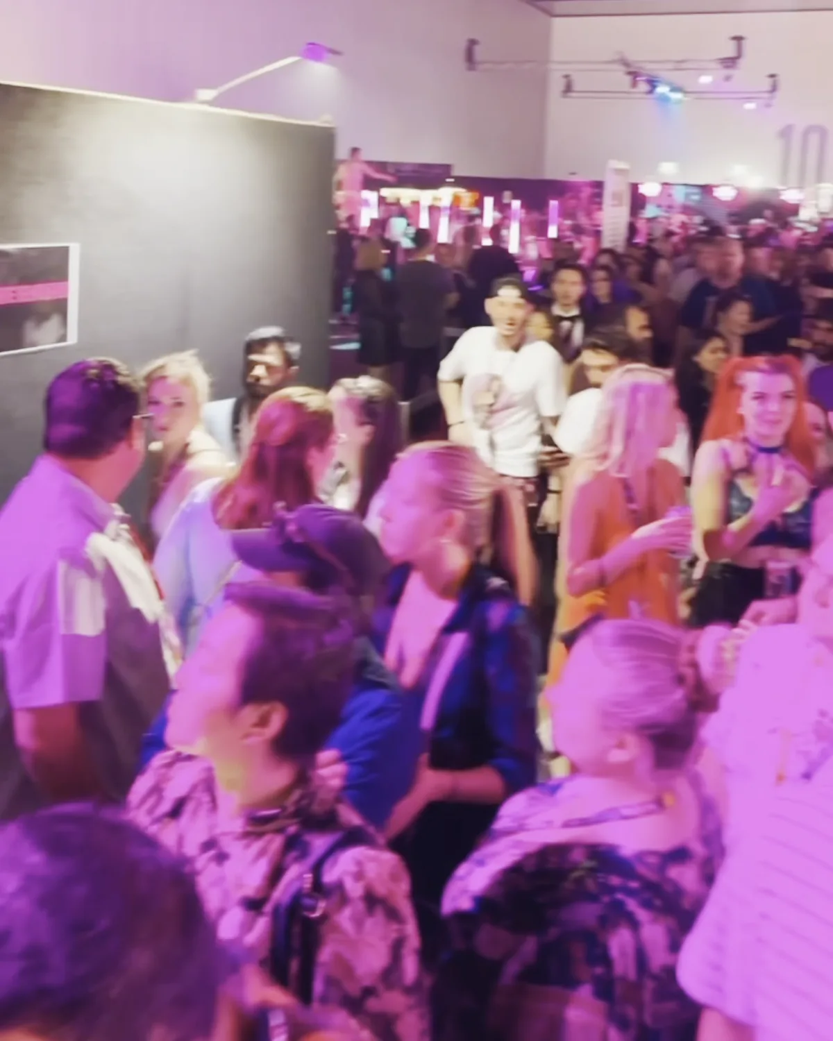 Guests mingling shoulder to shoulder at an industry night under a pink and violet wash