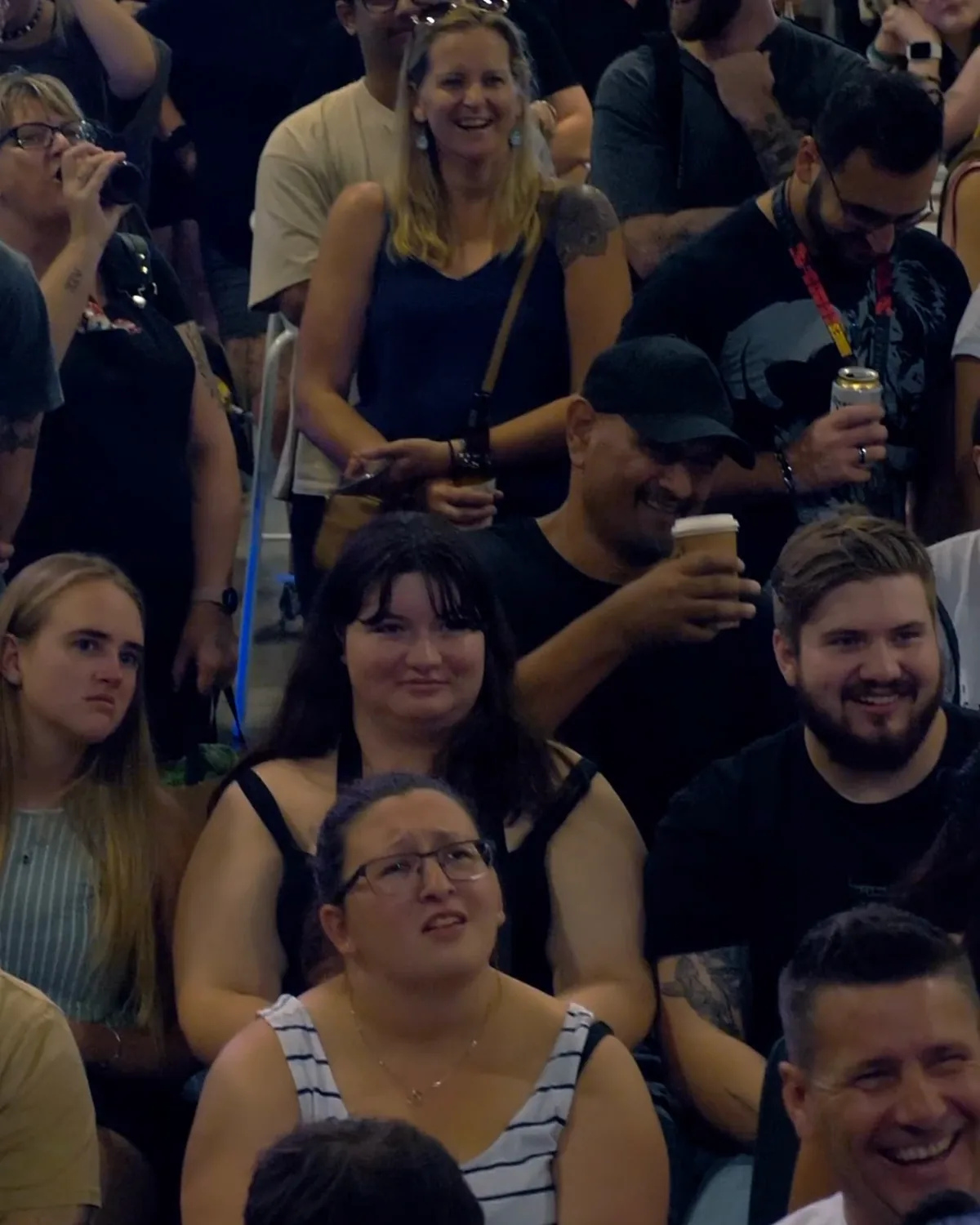 The front rows of a packed session, delegates laughing and filming the stage on their phones