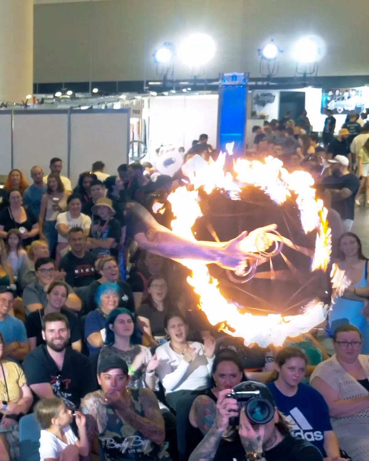 A fire performer spinning a burning hoop above a crowd pressed to the front of the stage