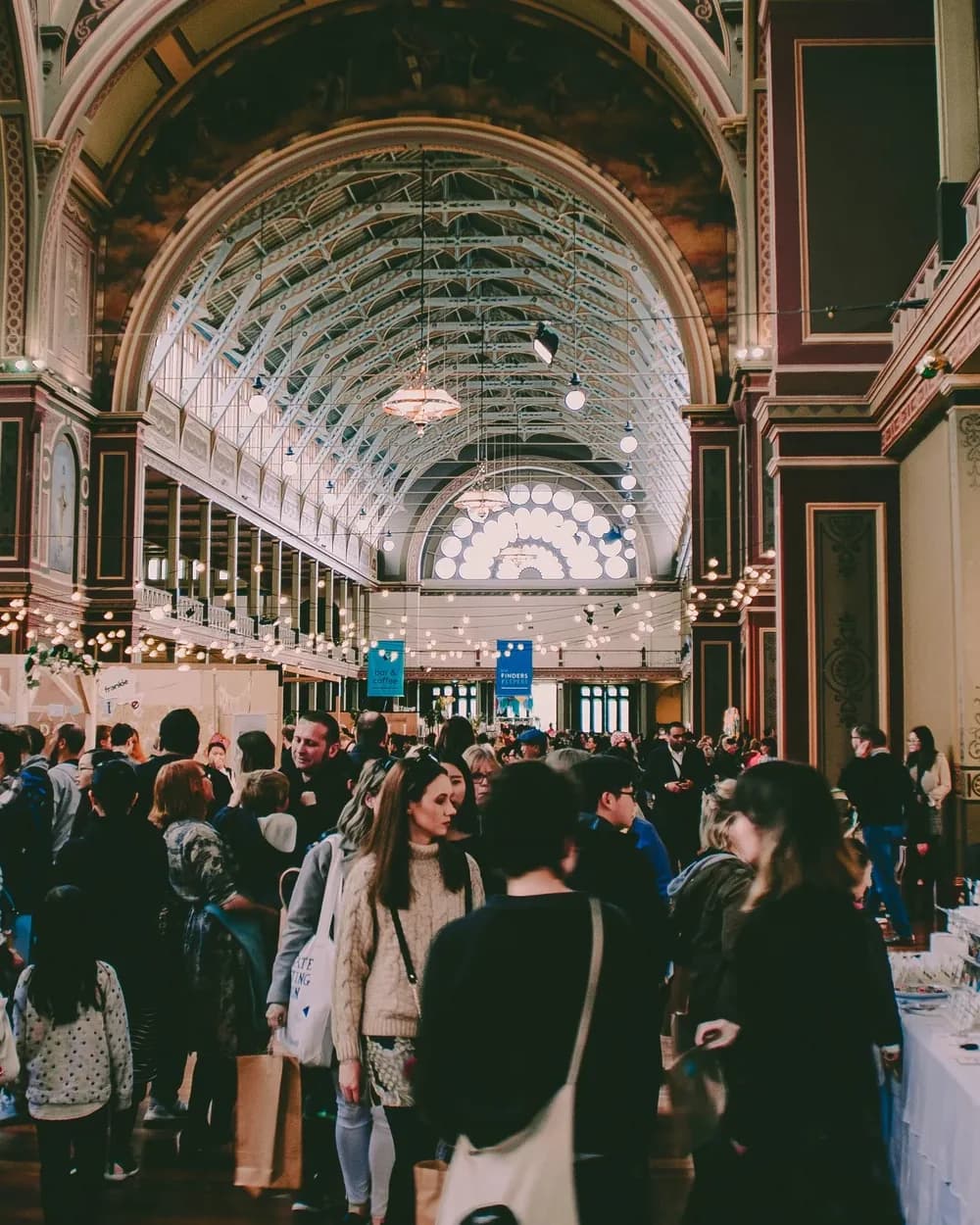 Buyers walking the stalls of a gift fair under the nave of a heritage exhibition building